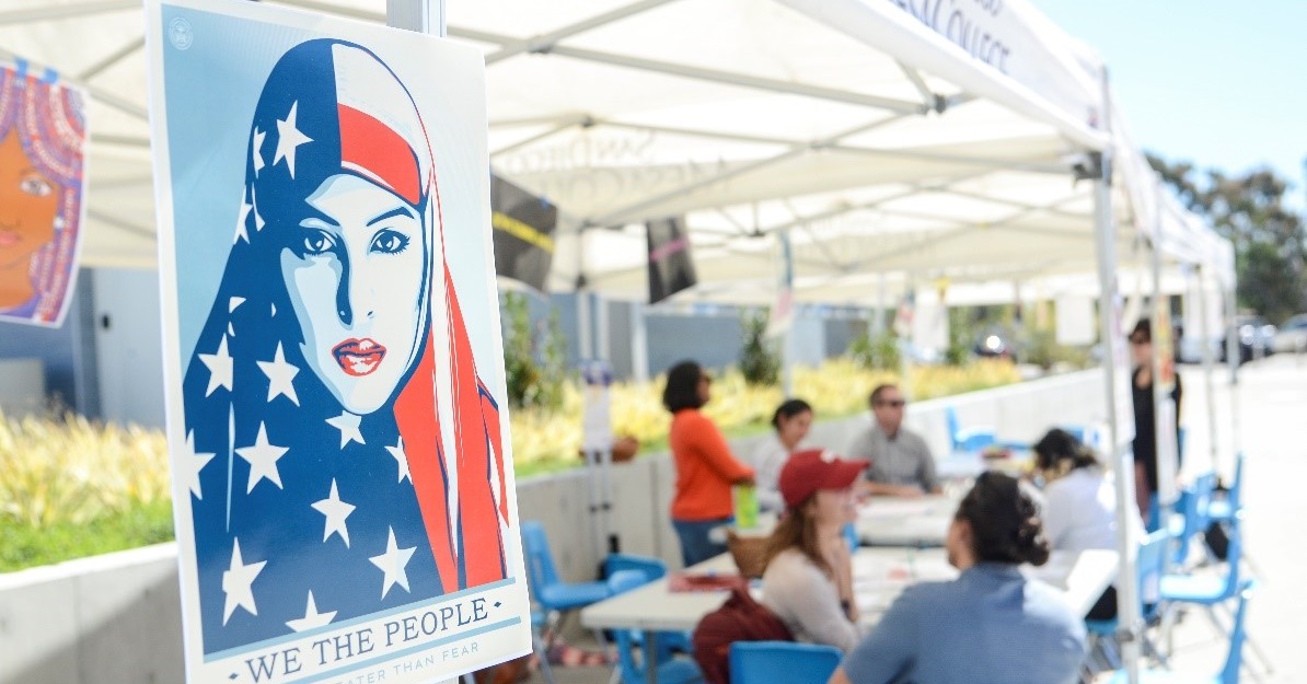 Voting event on campus with a 'We the People' poster depicting a woman with a stars and stripes hijab.
