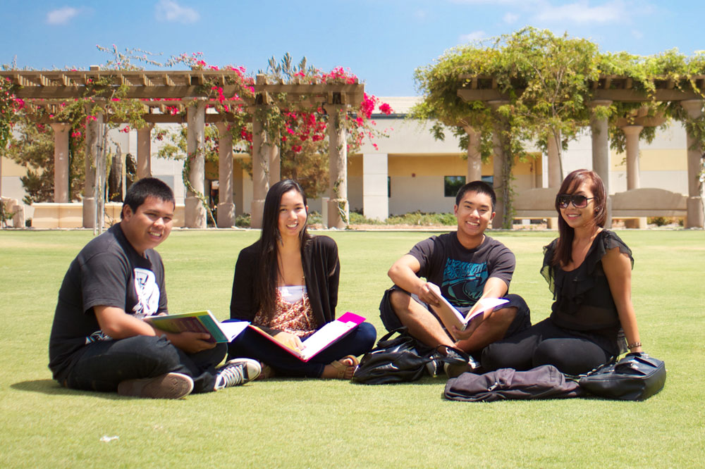 four students sit on the lawn
