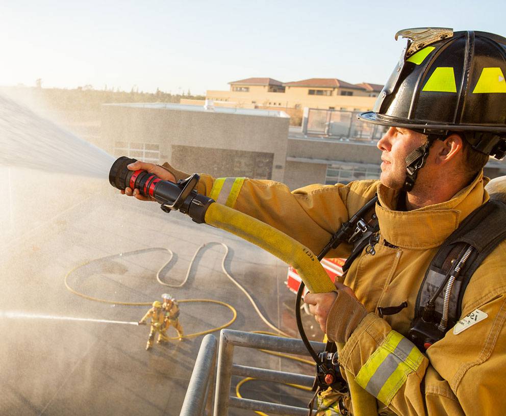 A fire trainee sprays a firehose