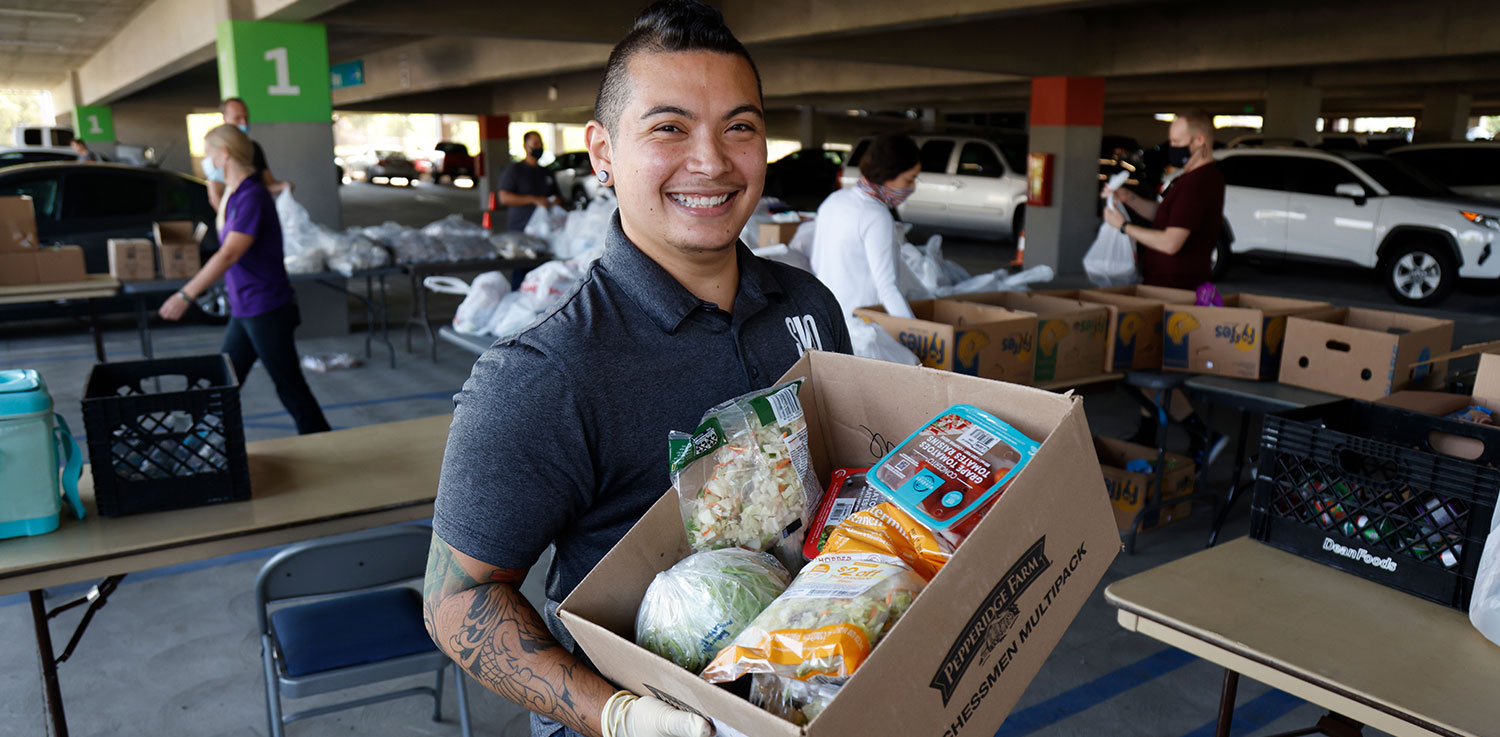 Amor Carchano holds a box of food while volunteering at a food drive.