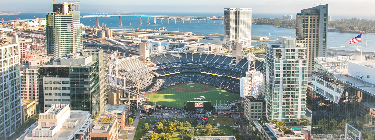 An aerial view of Petco Park baseball stadium surrounded by downtown San Diego with the Coronado Bridge in the background 