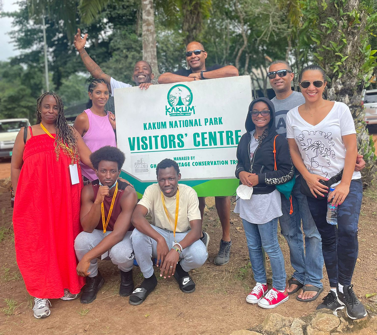 A group of city college students pose with a sign for a visitors center in Ghana