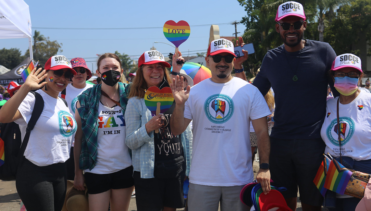 Six participants in the pride parade wave to the camera