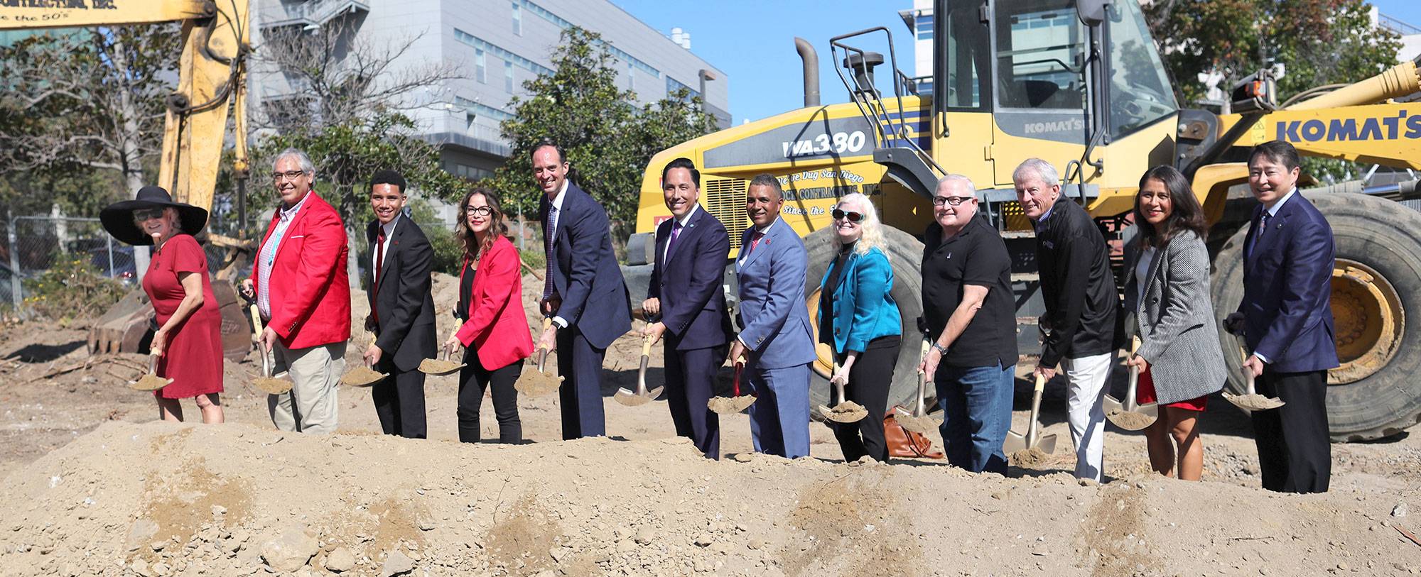 Twelve people hold shovels for a ceremonial groundbreaking photo