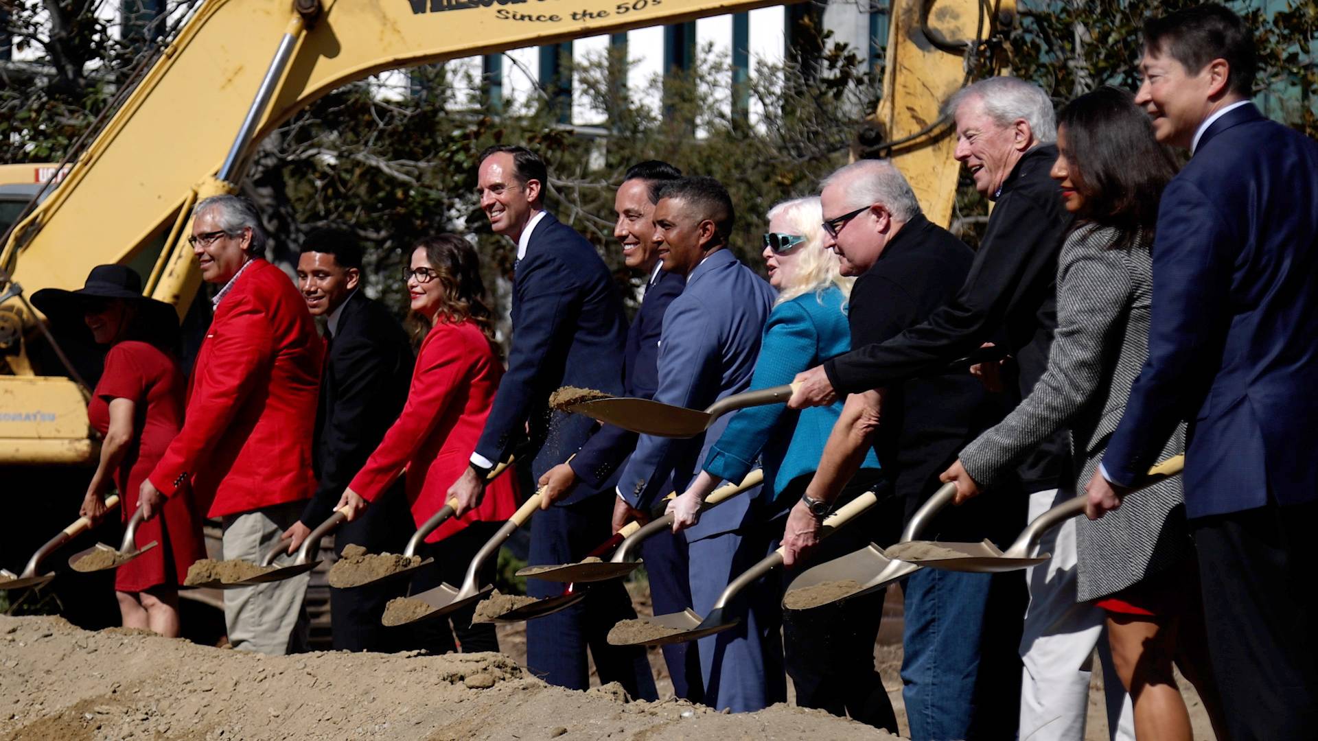 10 people shovel dirt at a groundbreaking event