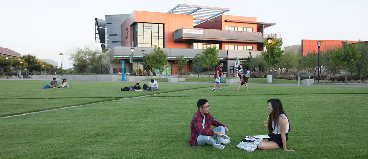 Two students sit on the grass at Compass Point at Miramar College