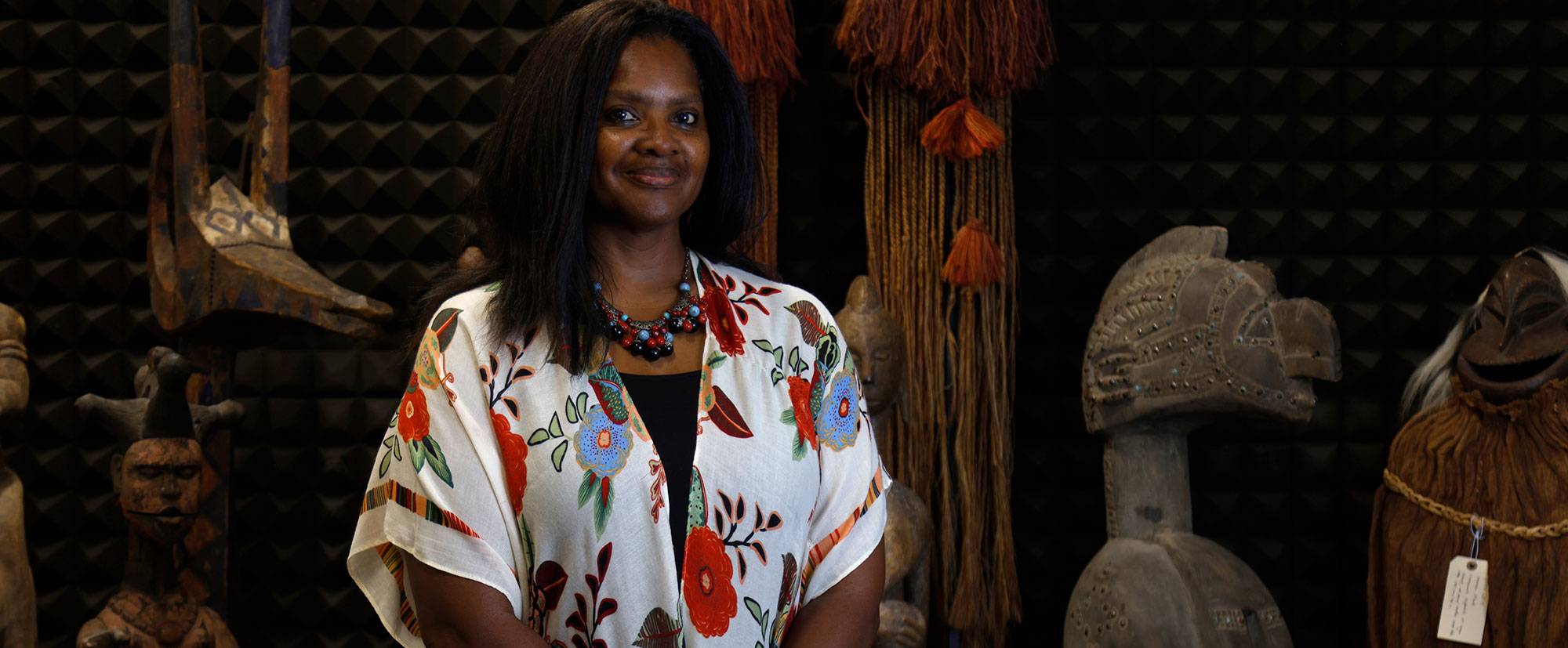 Dr. Denise Rogers stands in front of pieces in the World Art Collection