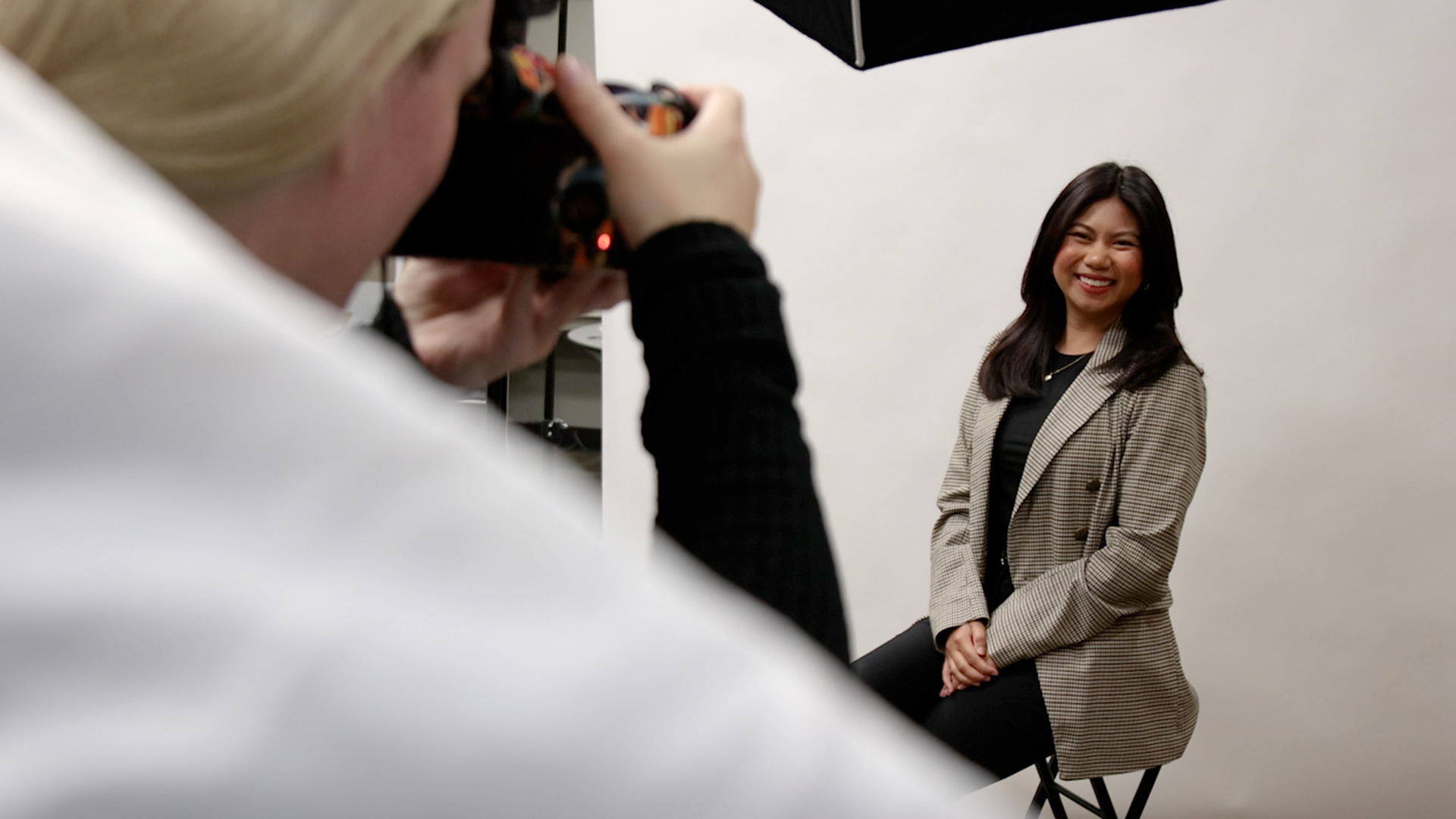 A student wearing a blazer has a professional headshot photo taken in a photo studio during the career fair