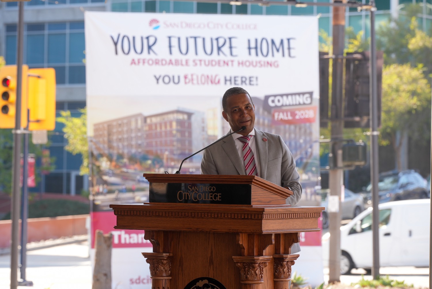 City College president at a podium in front of a sign that says your future home and an image of a future housing project.