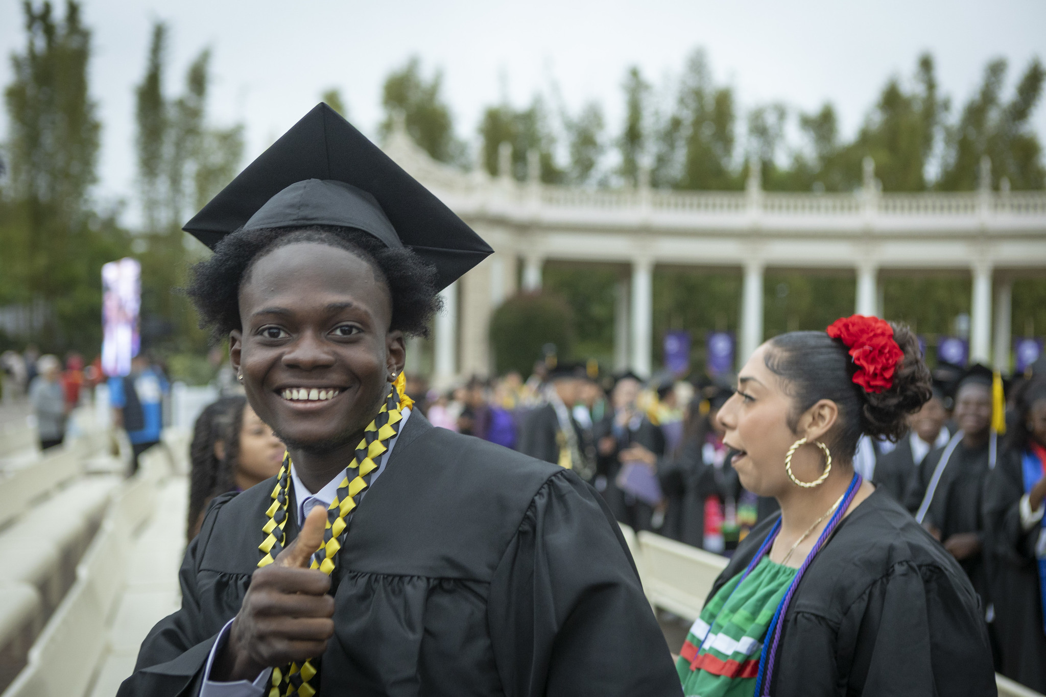 
A smiling graduate give a thumbs up.
