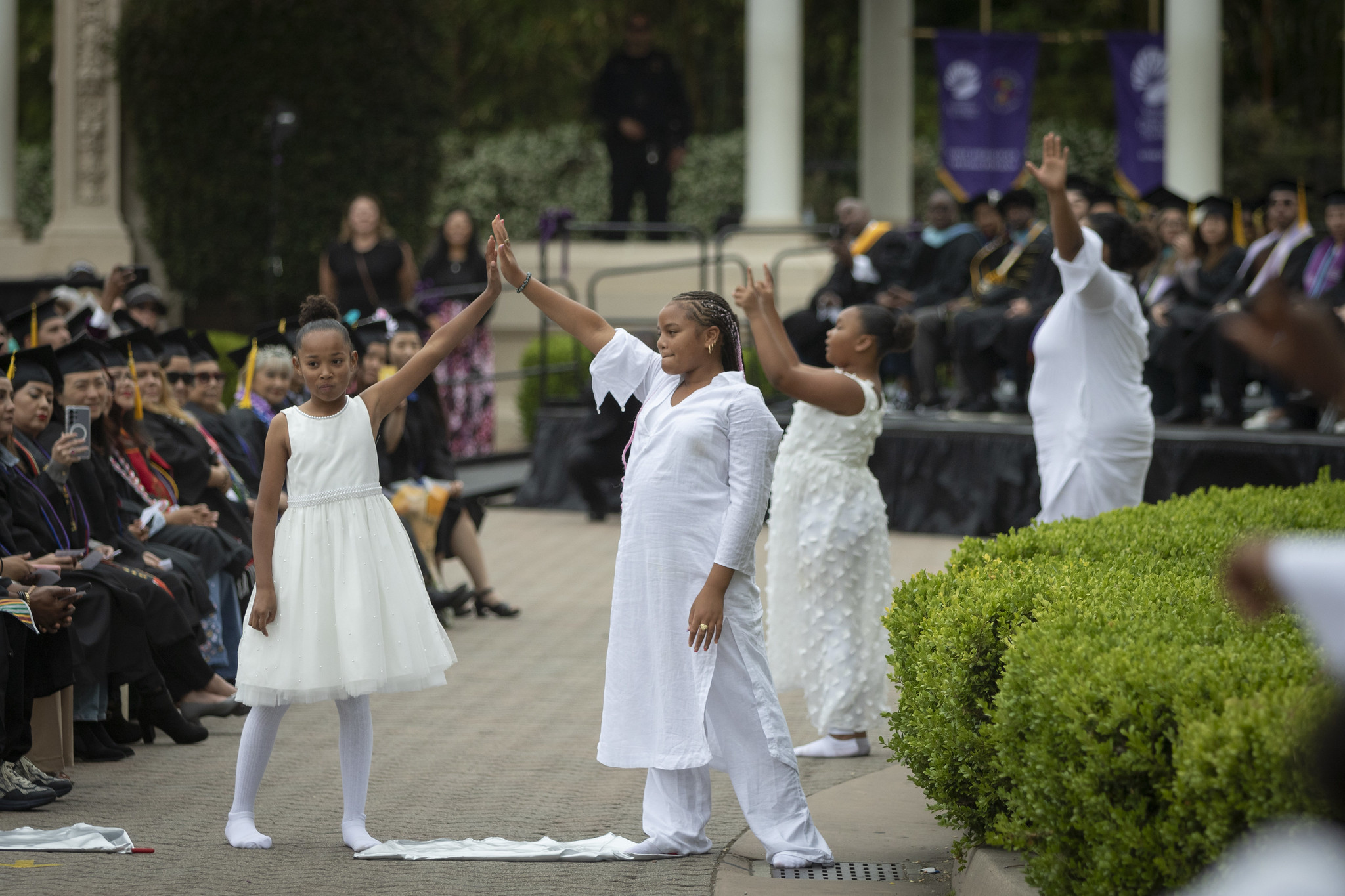 
Five children dressed in all white perform a dance at commencement.
