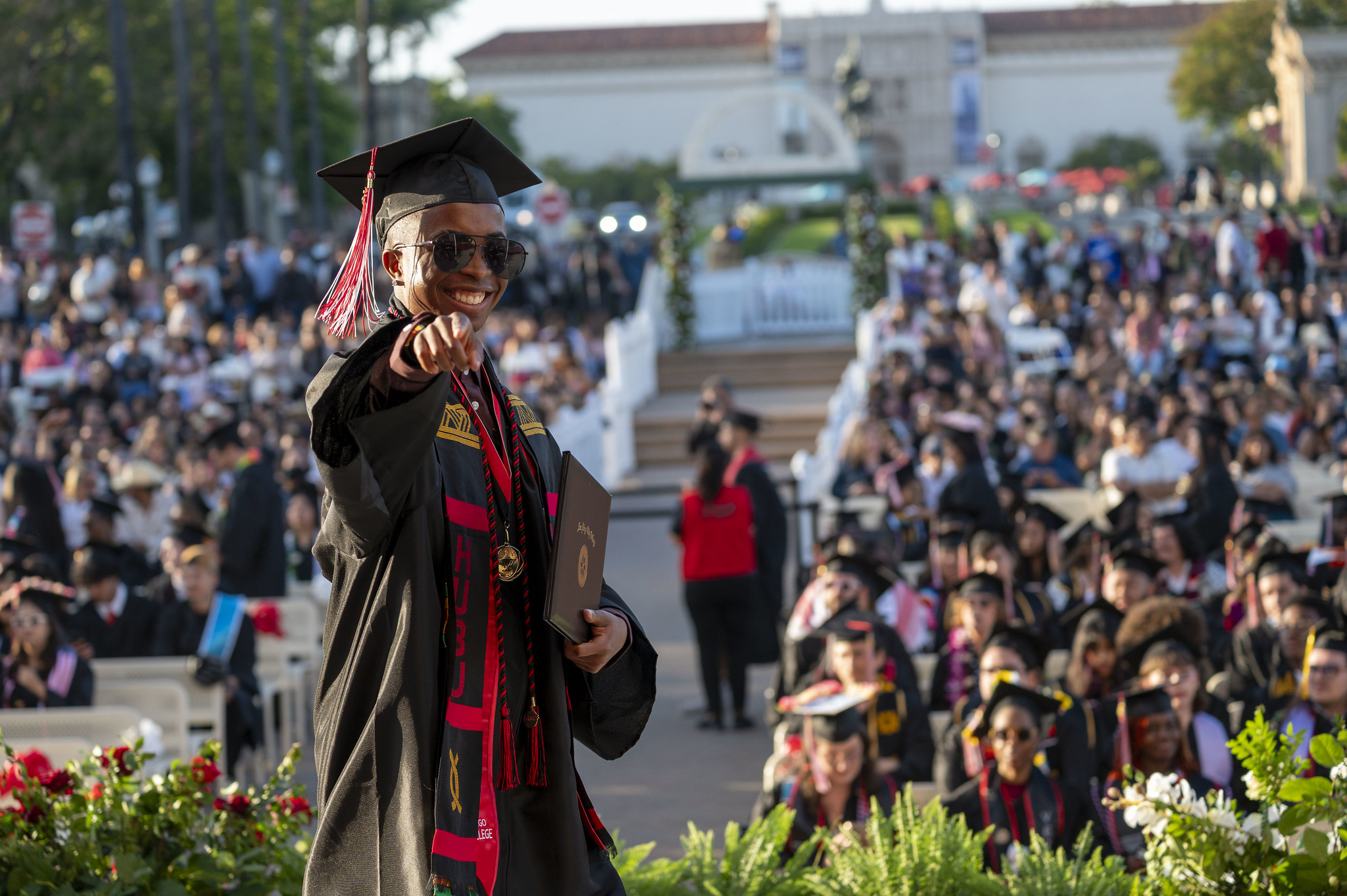
A student is smiling and points to the camera as he walks across the stage after receiving his diploma.
