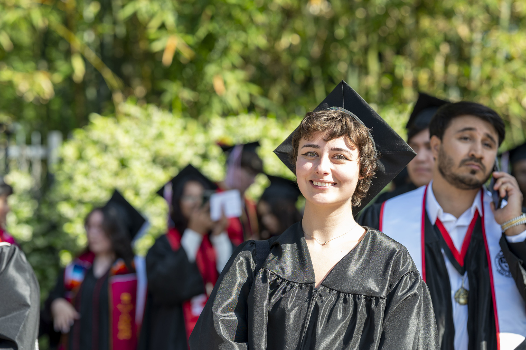
A graduate smiling while waiting in line to enter the ceremony.
