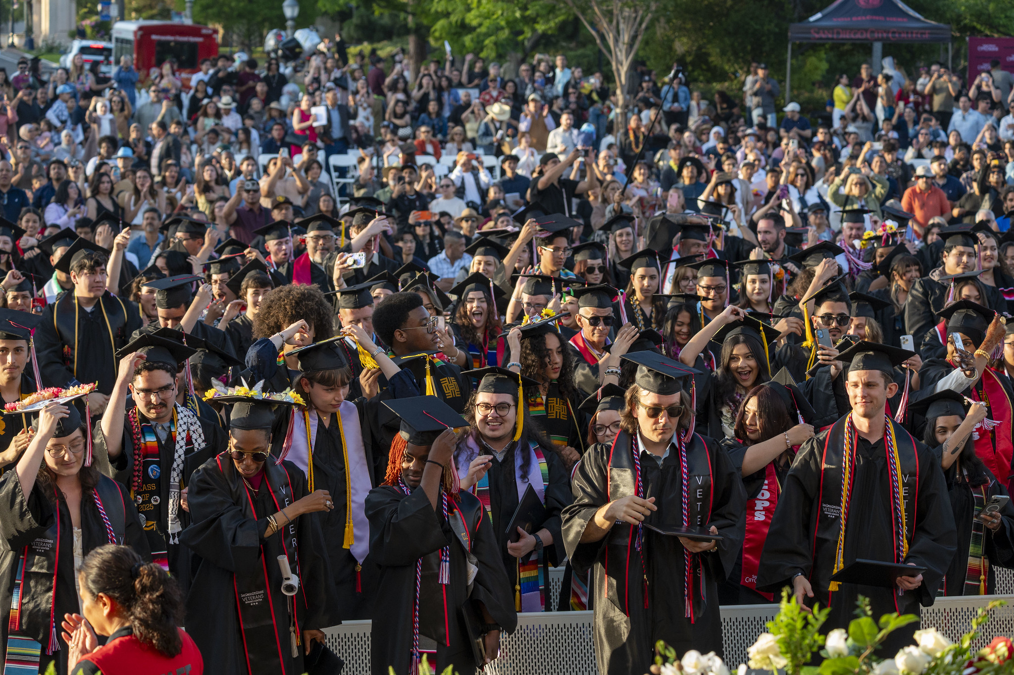 
All of the graduates in the audience stand to turn their tassels.
