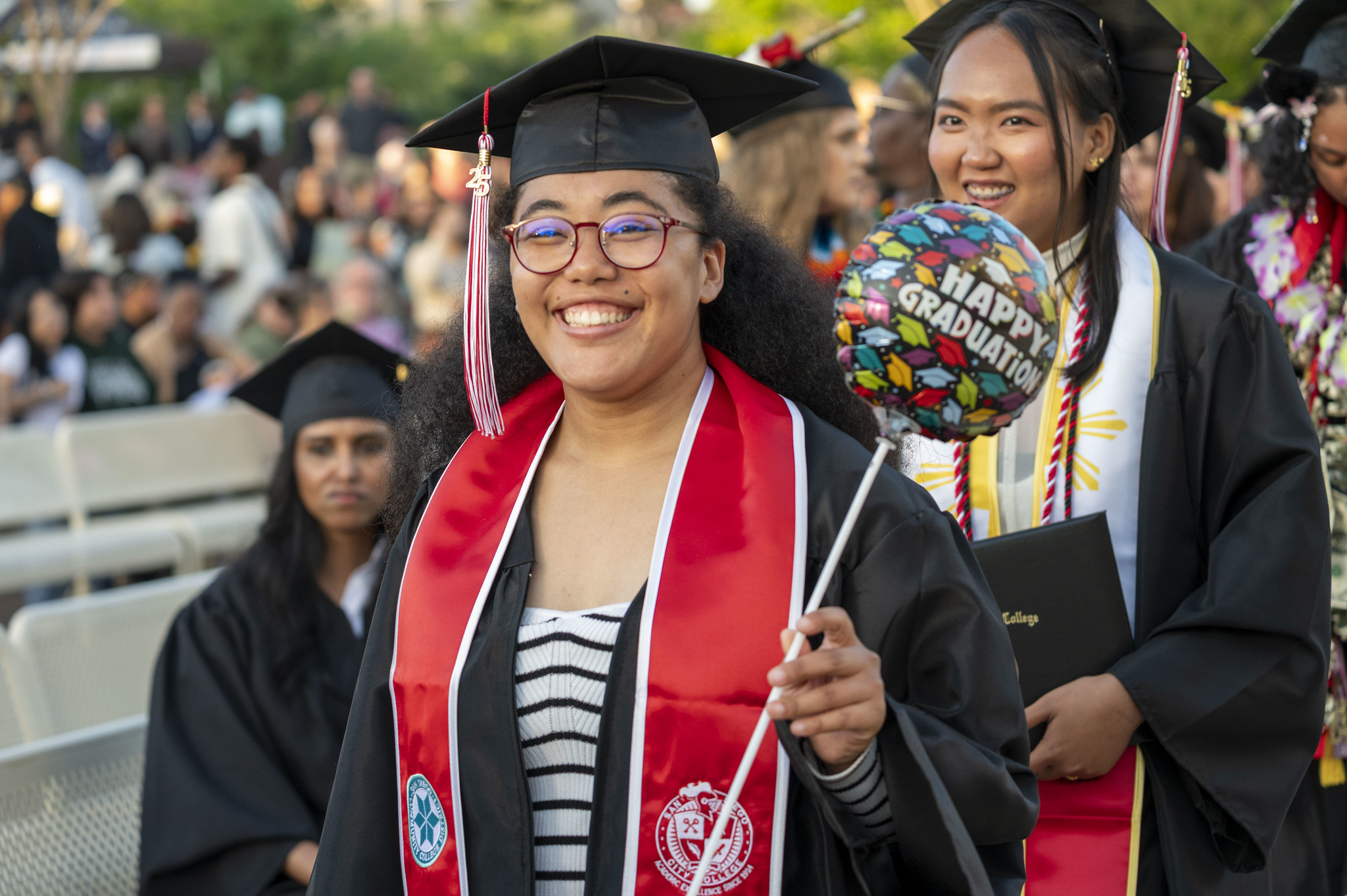 
A graduate with her degree and a small balloon that says happy graduation.
