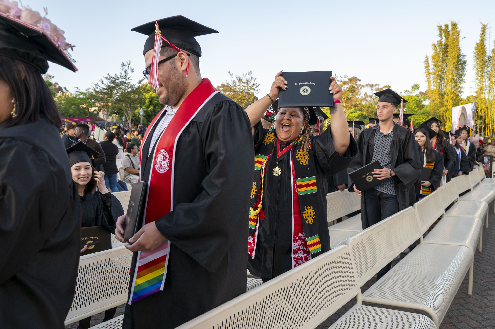 
A graduate in the audience holds up her degree.
