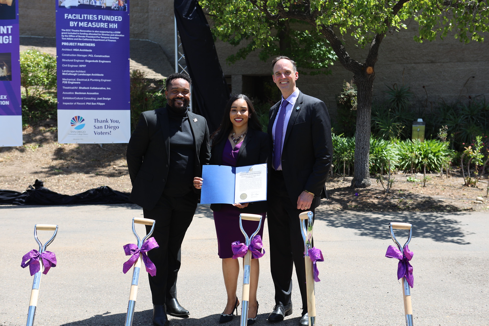 
Three people holding up a folder

