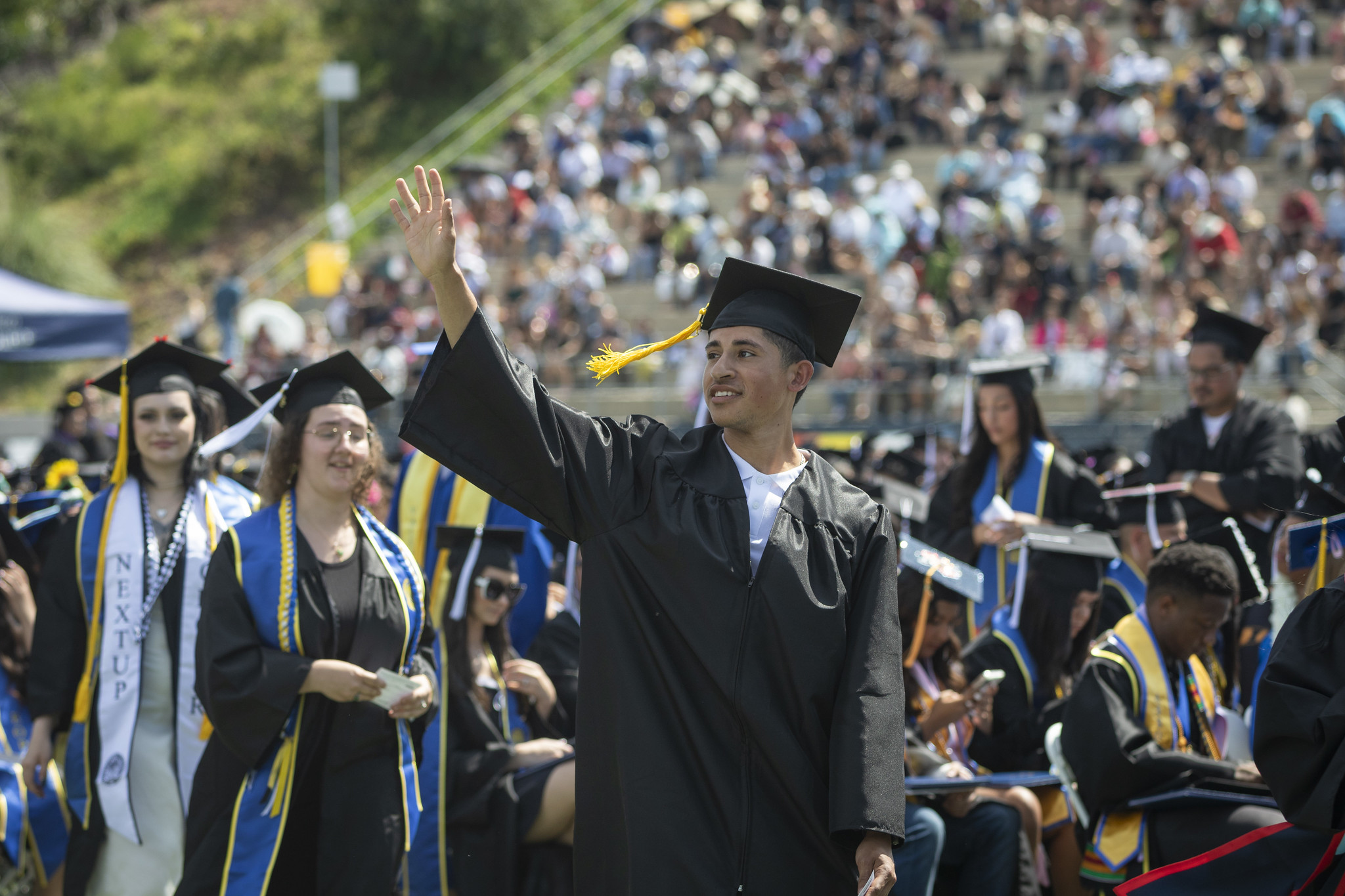 
A graduate waves to the crowd as he takes his seat.
