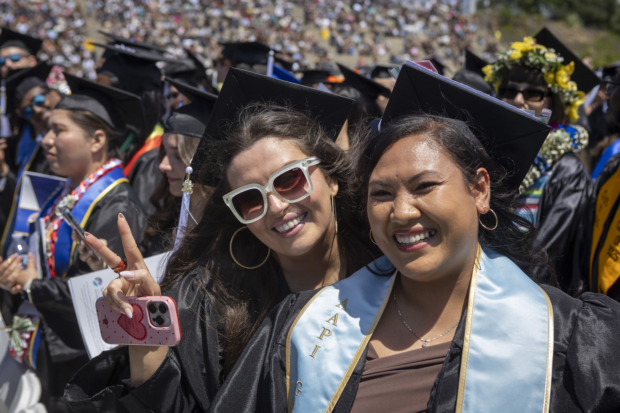 
Two graduates in the crowd celebrating.
