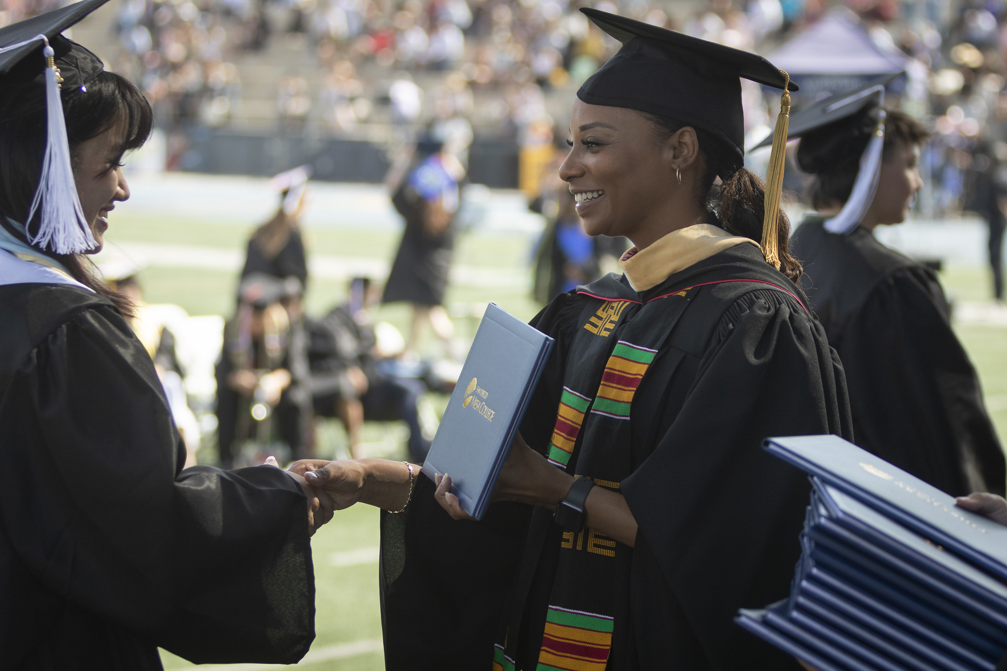 
Trustee Mariah Jameson shakes a graduate's hand and gives her a diploma.
