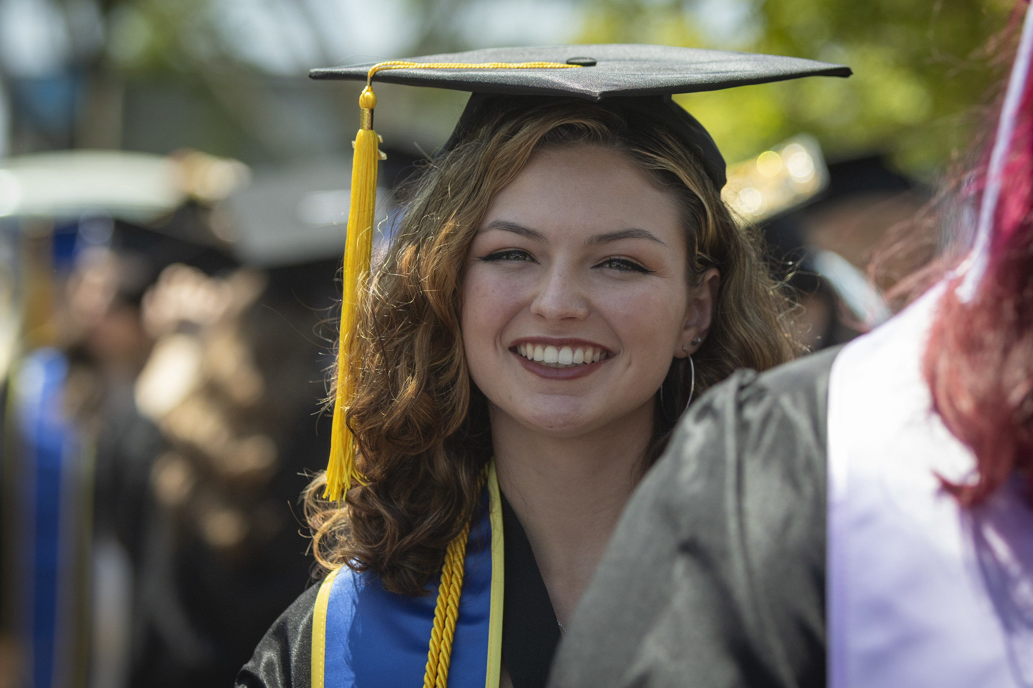 
A graduate smiling in a crowd.
