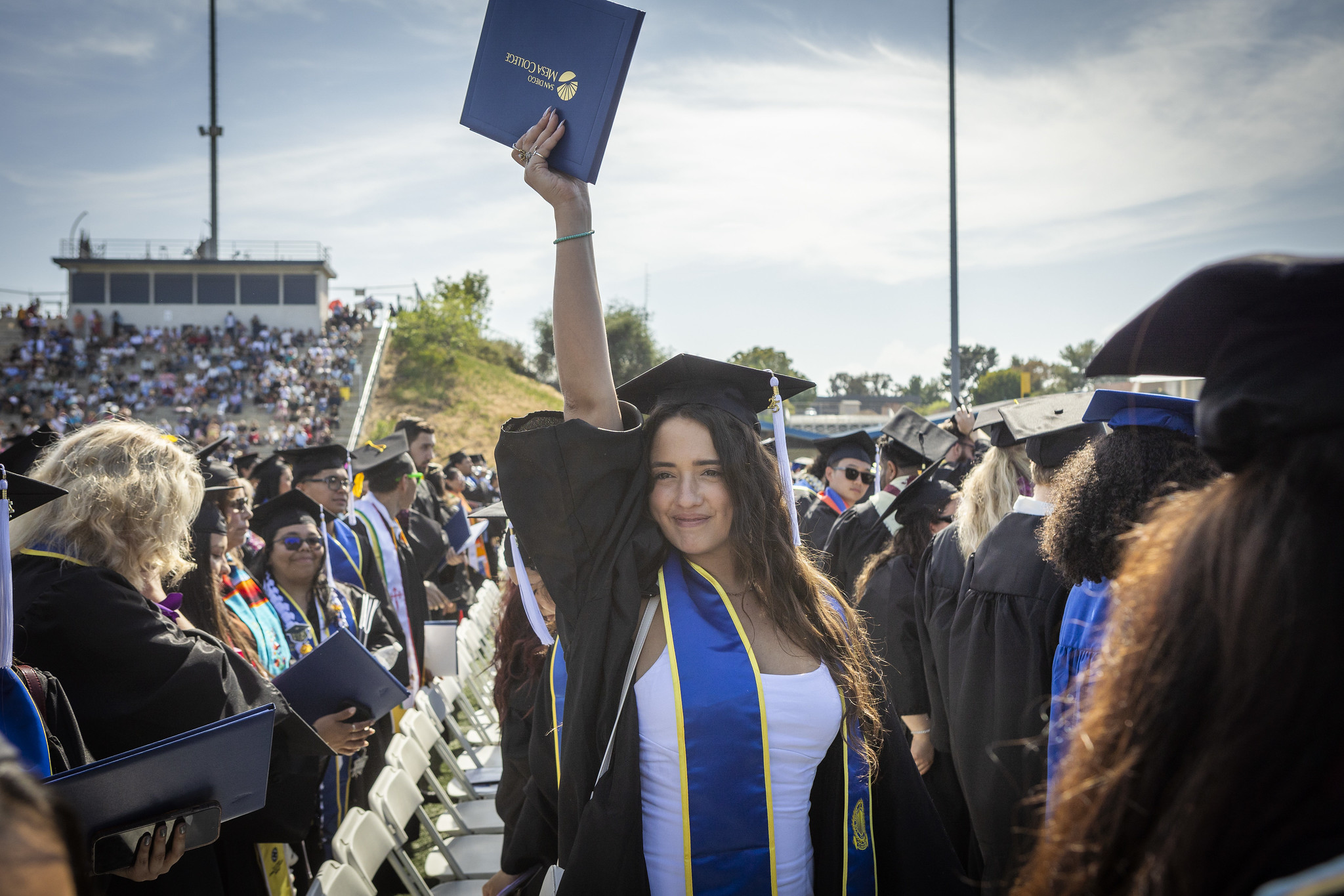 
A graduate holds up her degree over her head.
