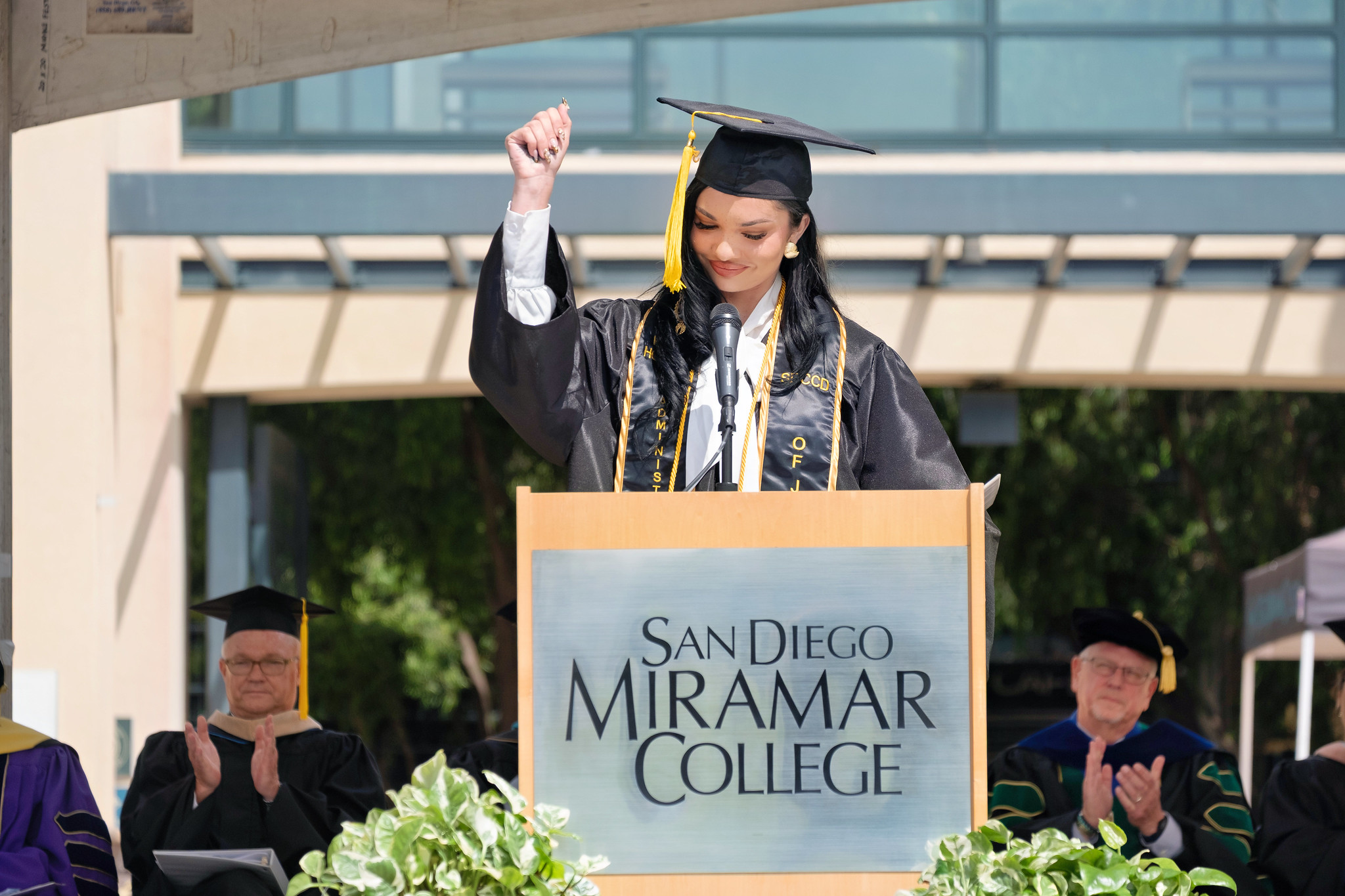 
The student commencement speaker in a black cap and gown at the podium
