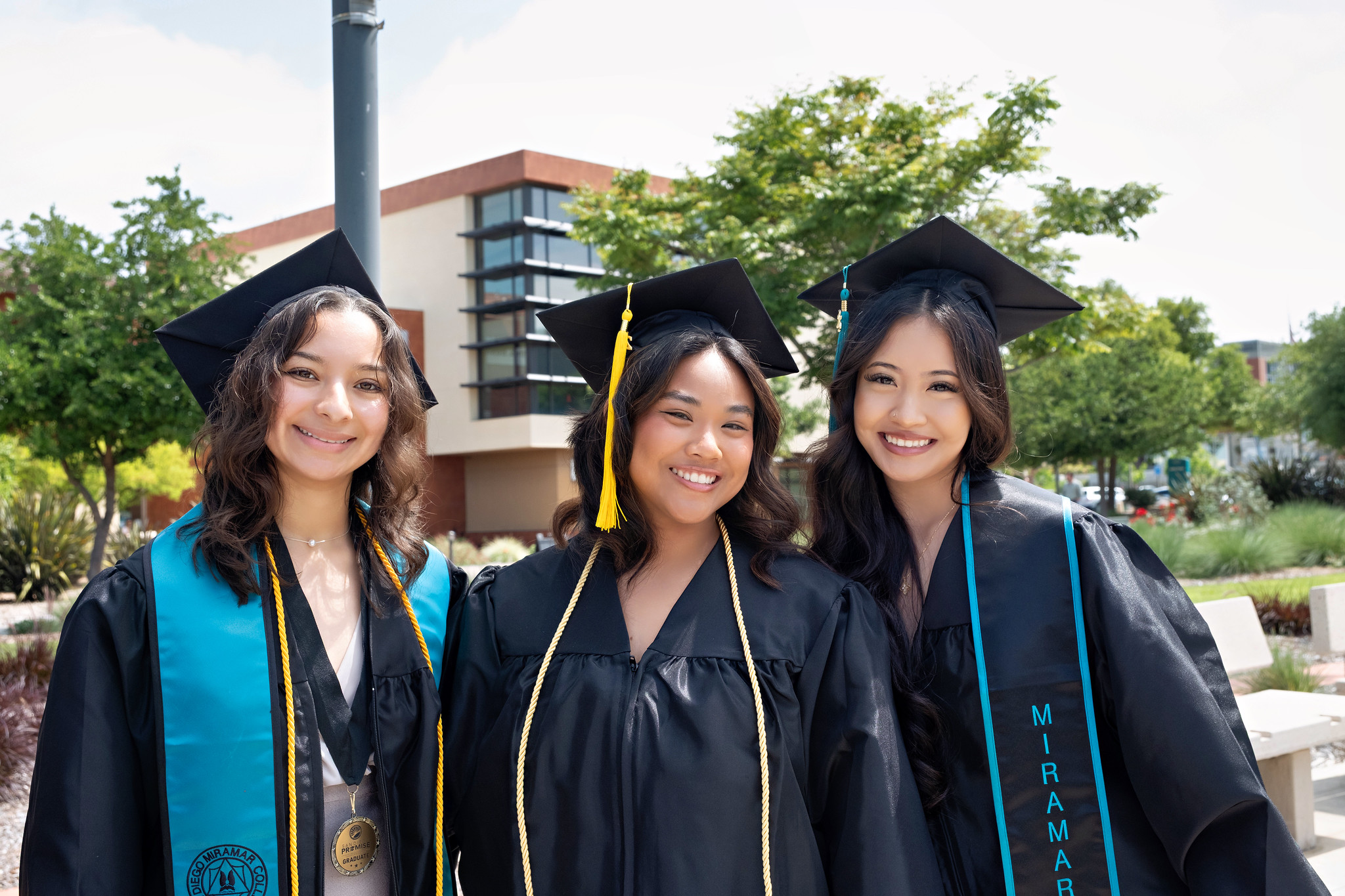 
Three graduates in black caps and gowns.
