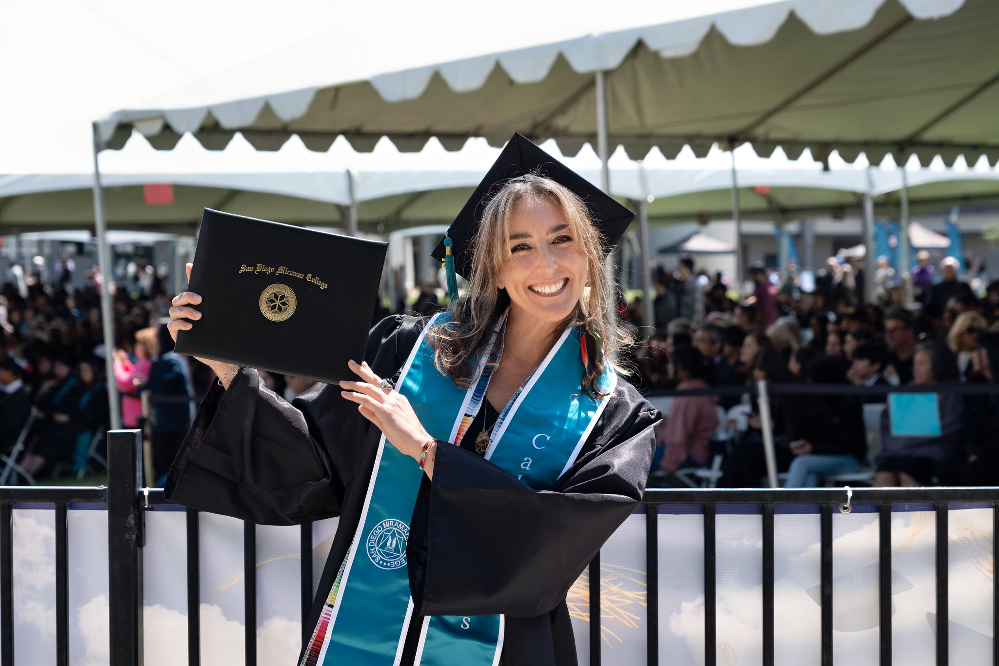 
A student holds up her degree.
