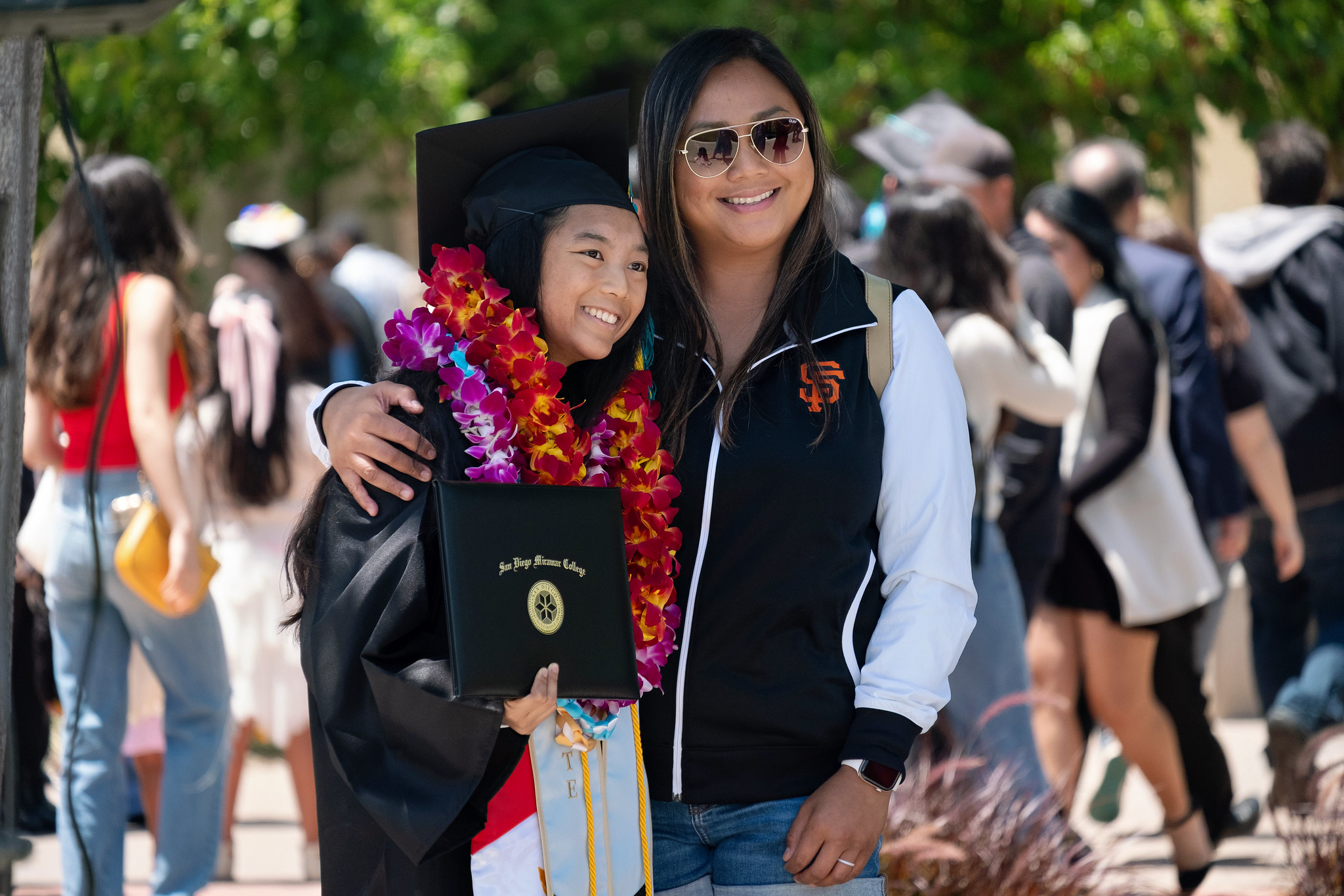 
A graduate with her degree gets a hug from a family member.

