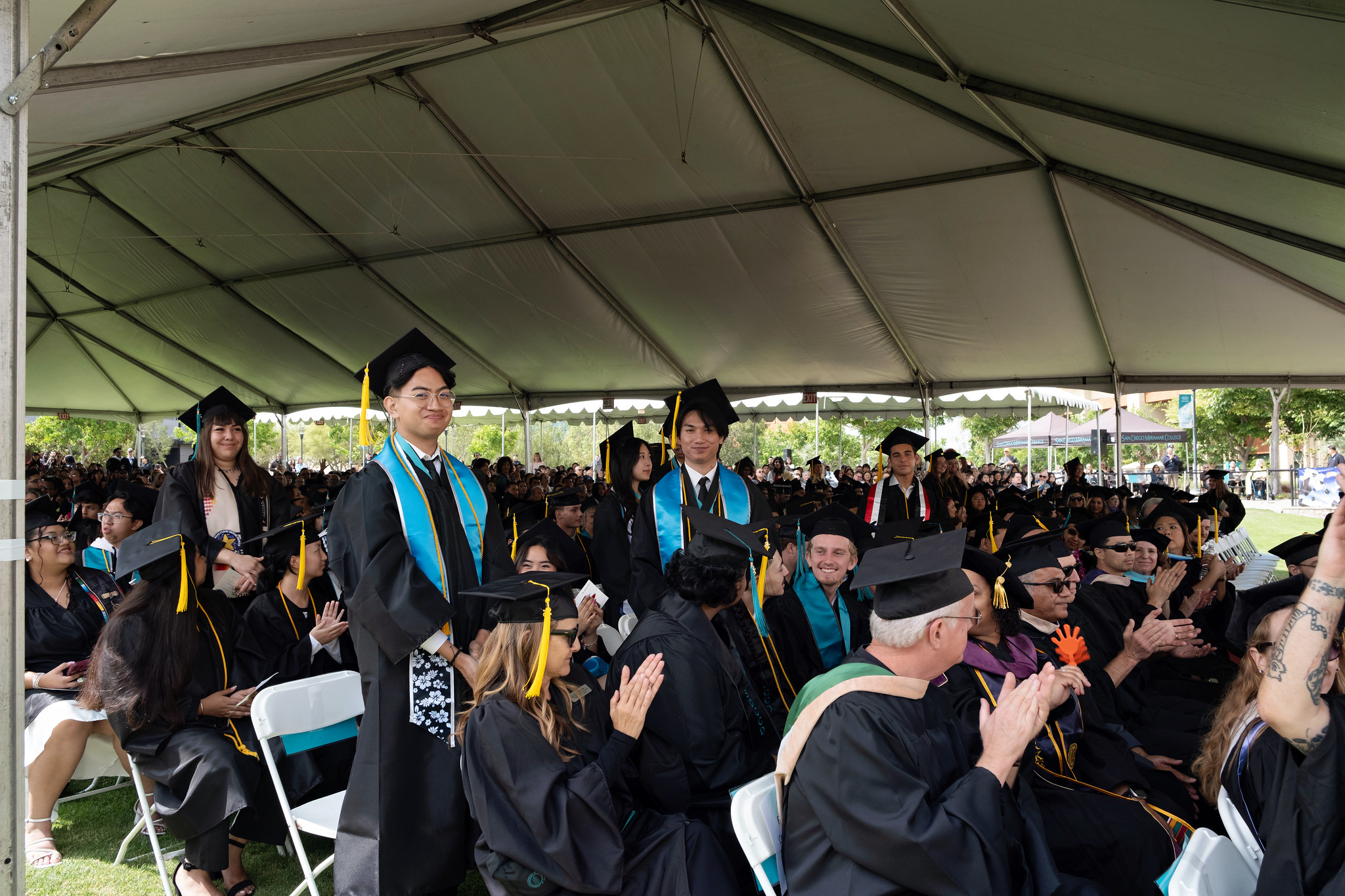
Faculty and students seated under a canopy during commencement.
