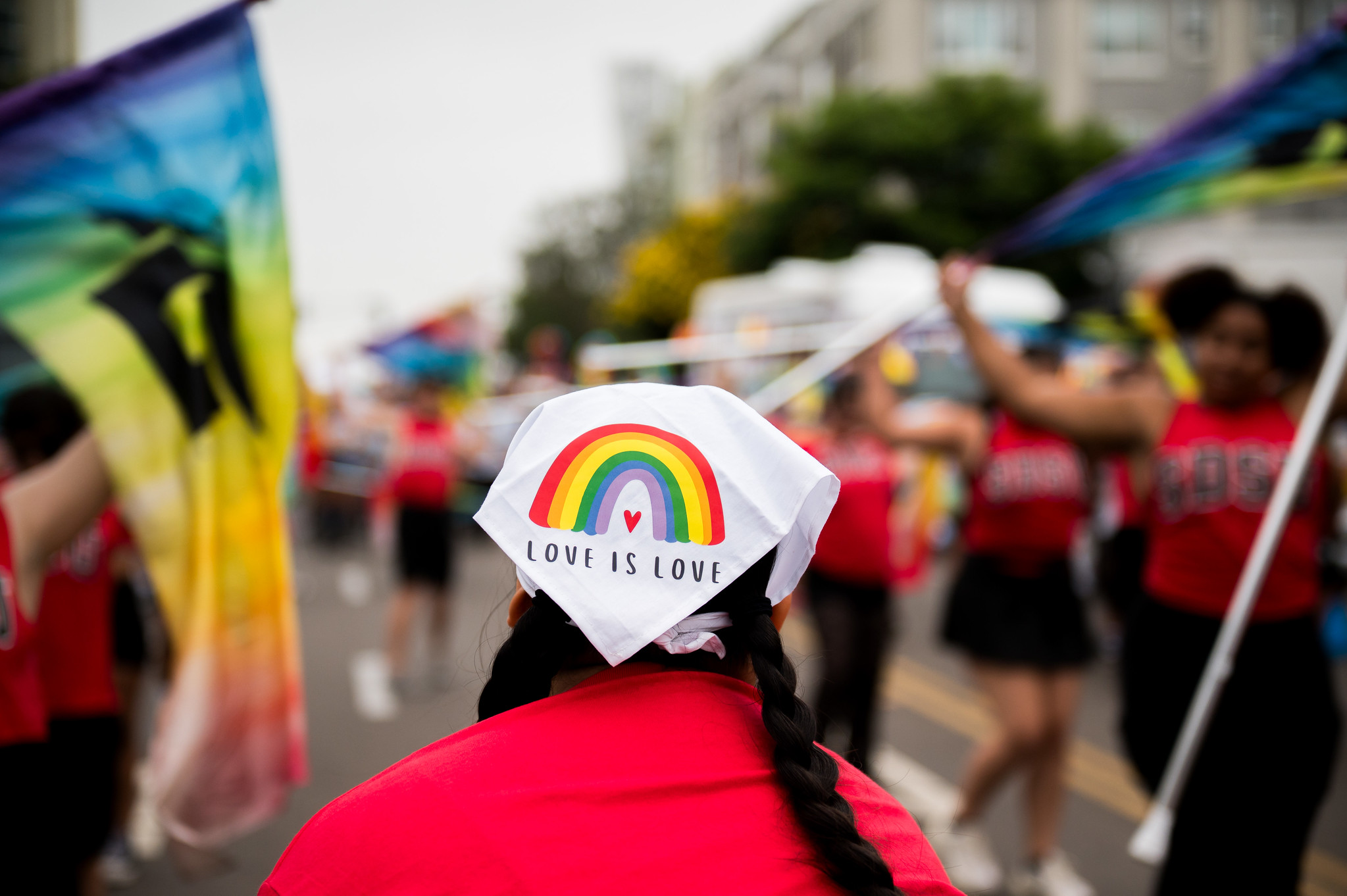 
A woman wears a white bandana in her hair with a rainbow that says love is love.

