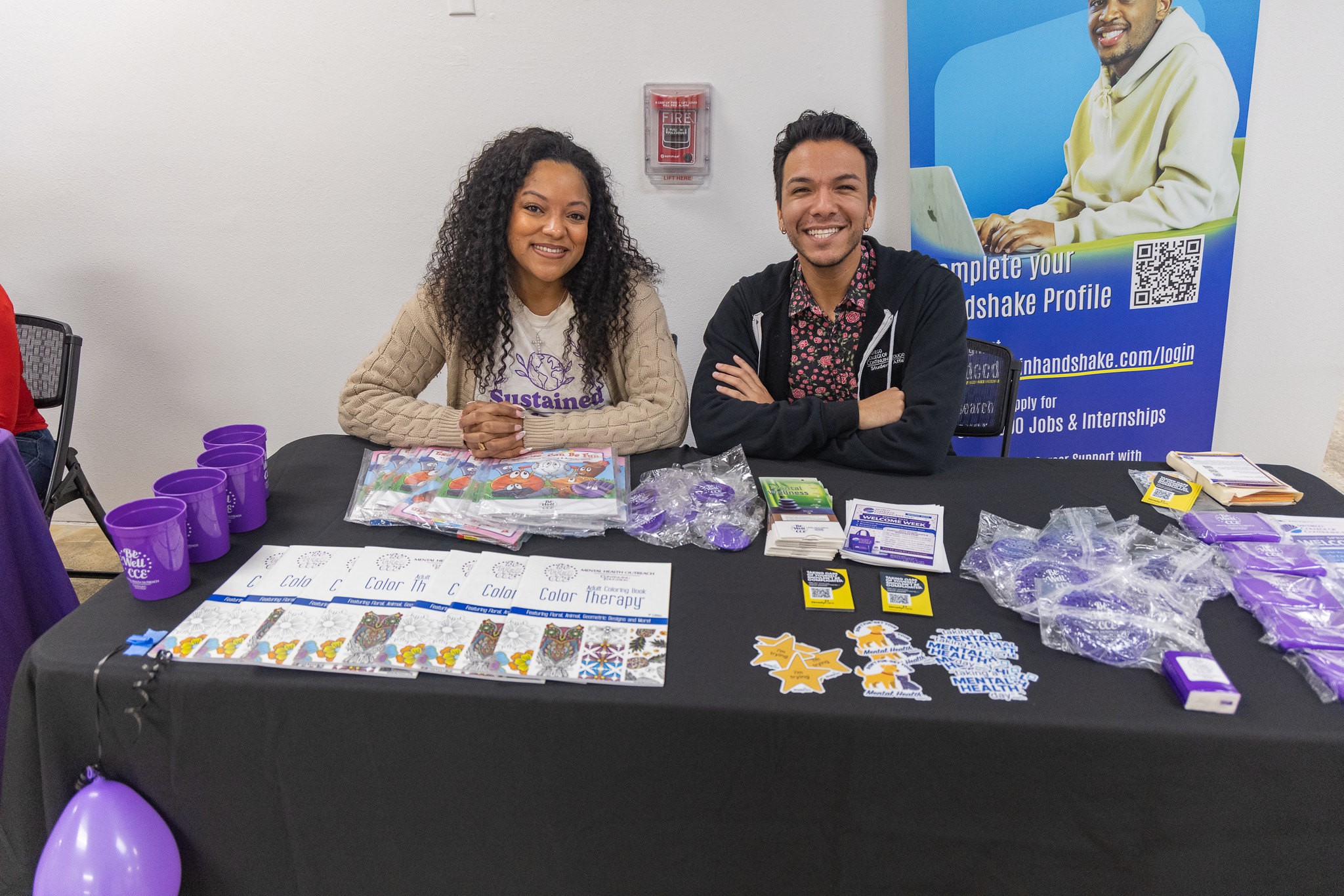 
Two employees seated at a Continuing Education welcome table.
