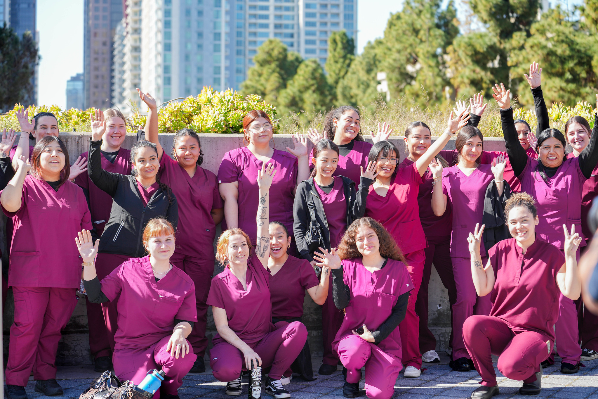 
19 City College nursing students in red scrubs take a group photo.
