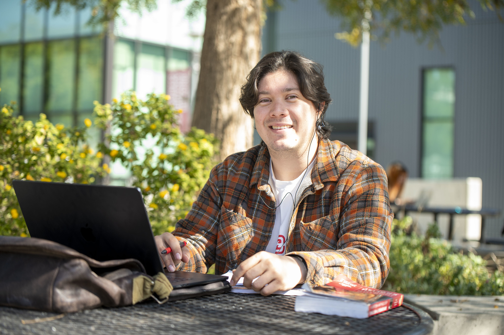 
A City College student at an outside table works on a laptop.
