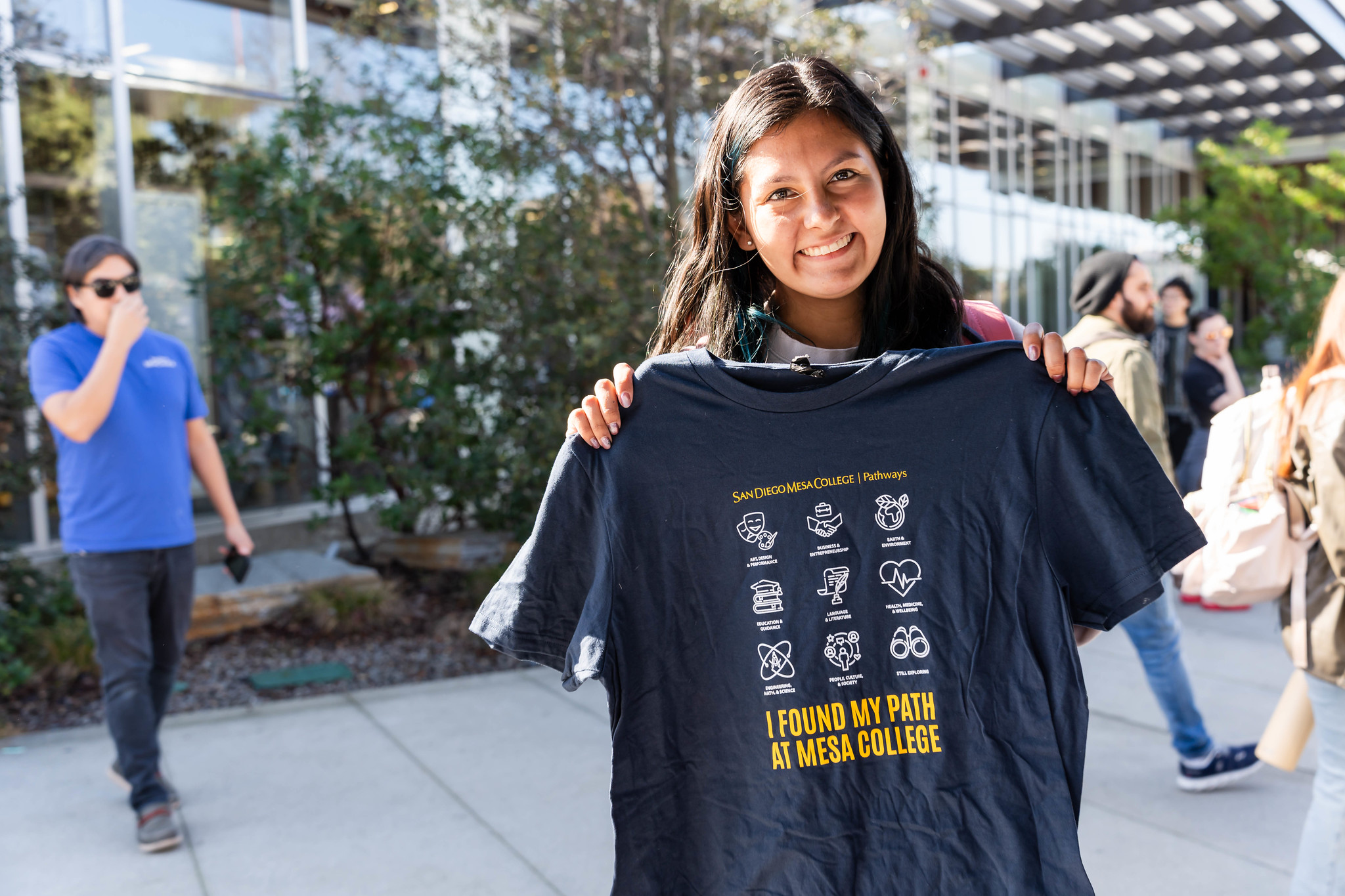 
A student holds up a blue Mesa College t-shirt.
